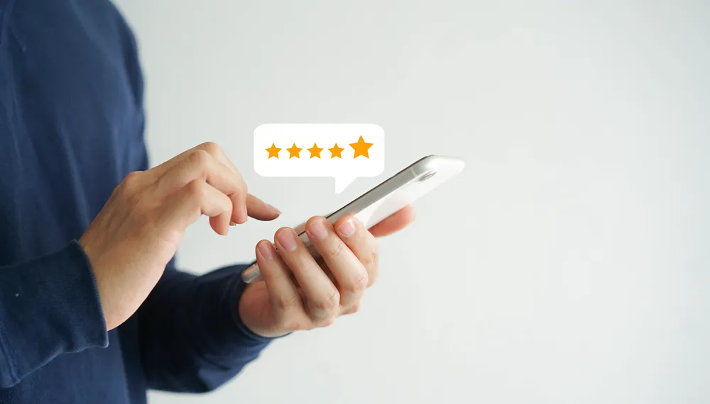 Person using smartphone to leave a five-star review, illustrating online reputation management and customer feedback engagement.