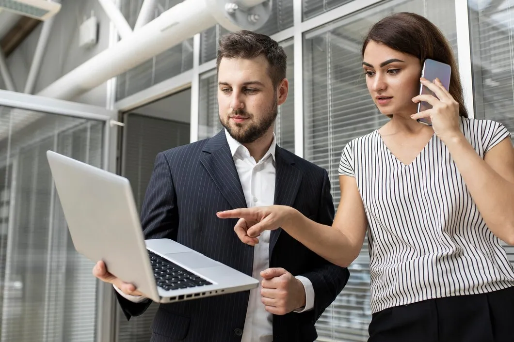 Colleagues discussing business strategy while reviewing data on a laptop in a modern office setting.