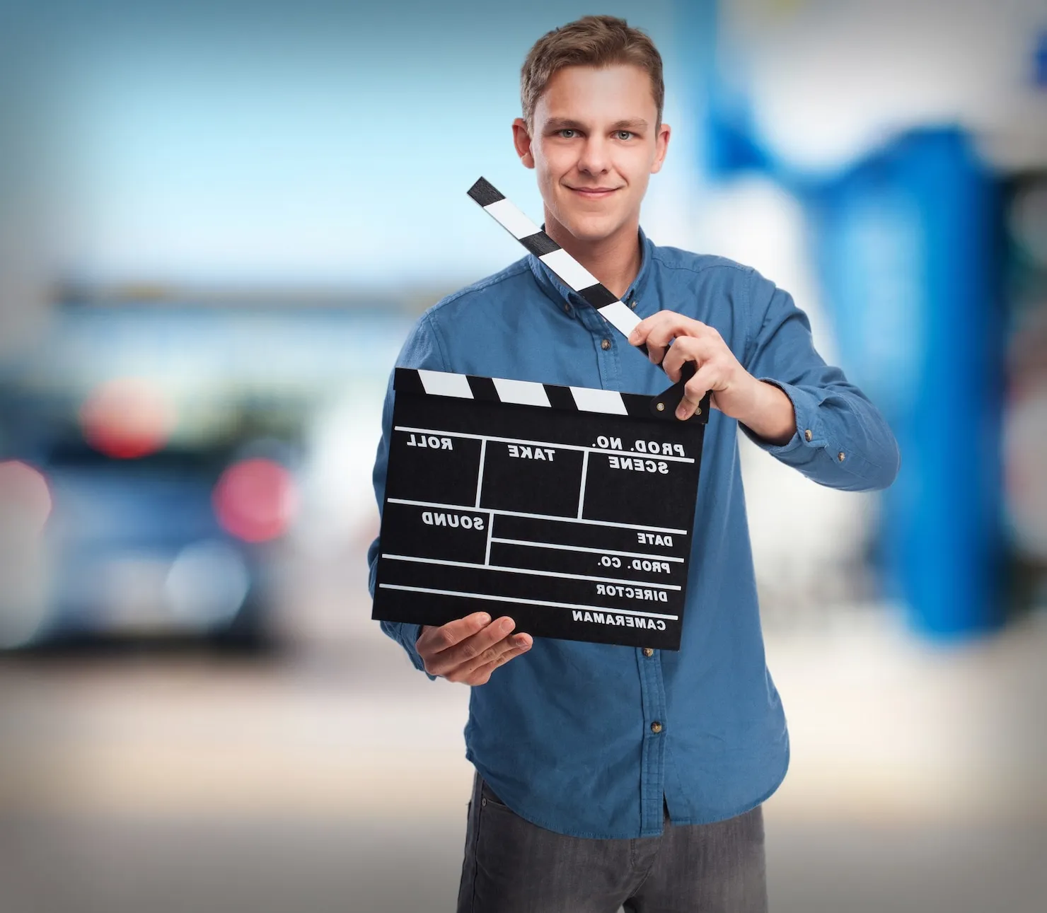 Young man holding a clapperboard, symbolizing video production and creativity, relevant to Marketania's video quote services.