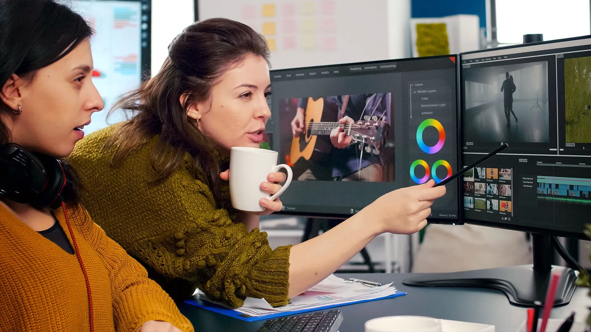 Two women collaborating in a video production setting, one holding a coffee cup and pointing at editing software on a monitor, showcasing visual storytelling and video editing processes.