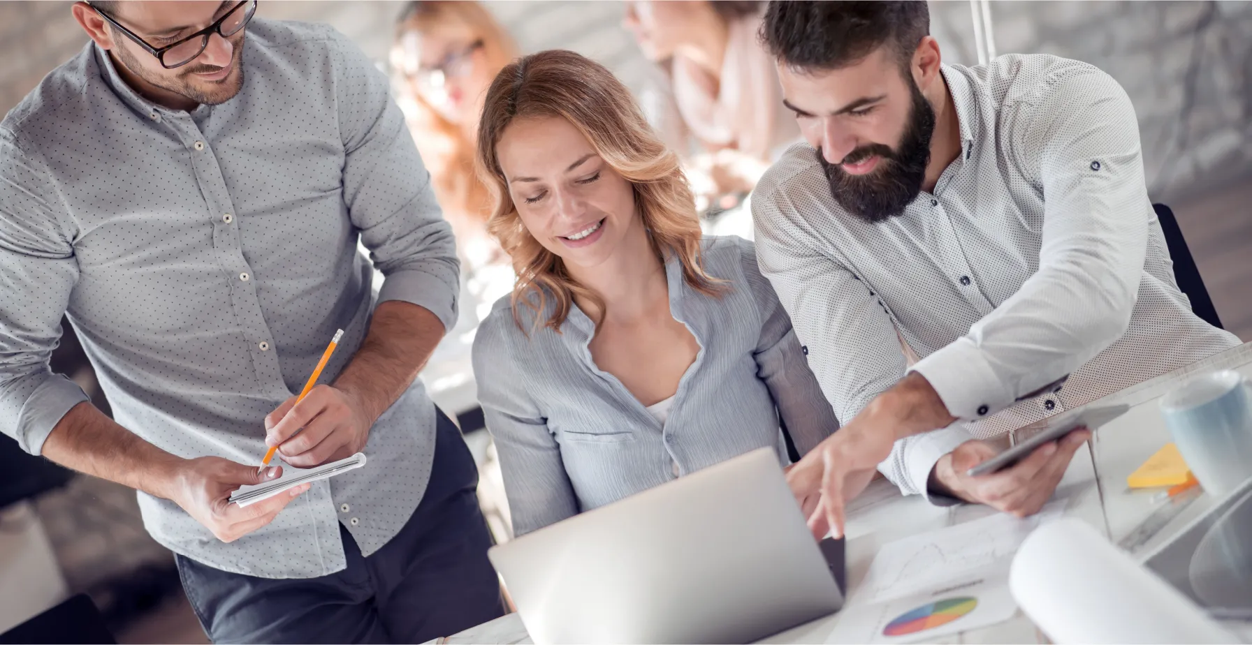 Team collaboration in a modern office setting, discussing digital solutions and strategies, focused on a laptop, emphasizing business growth and technology integration.