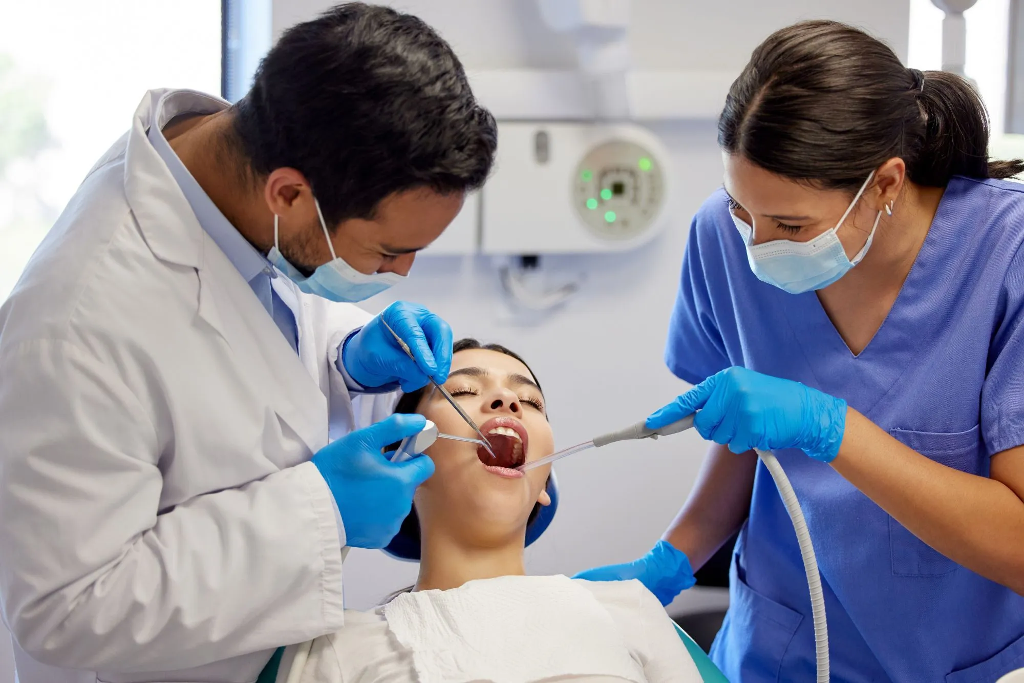 Dentist and dental assistant performing a procedure on a patient in a modern dental office, emphasizing patient care and professional dental services.