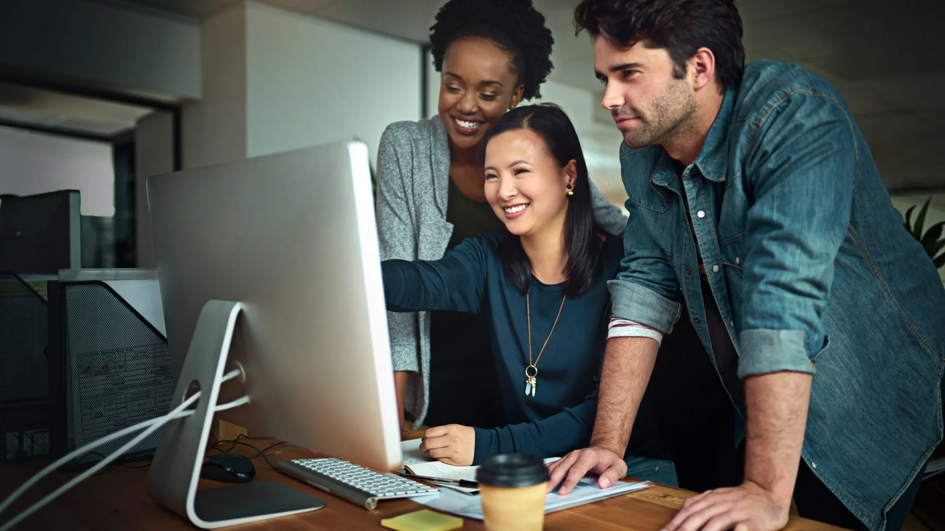 Team collaborating at a computer, discussing digital marketing strategies, emphasizing topical authority and SEO optimization.