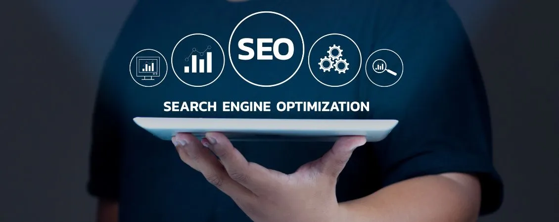 Hand holding a tablet displaying SEO icons and text, emphasizing search engine optimization services for improved website visibility and organic growth.
