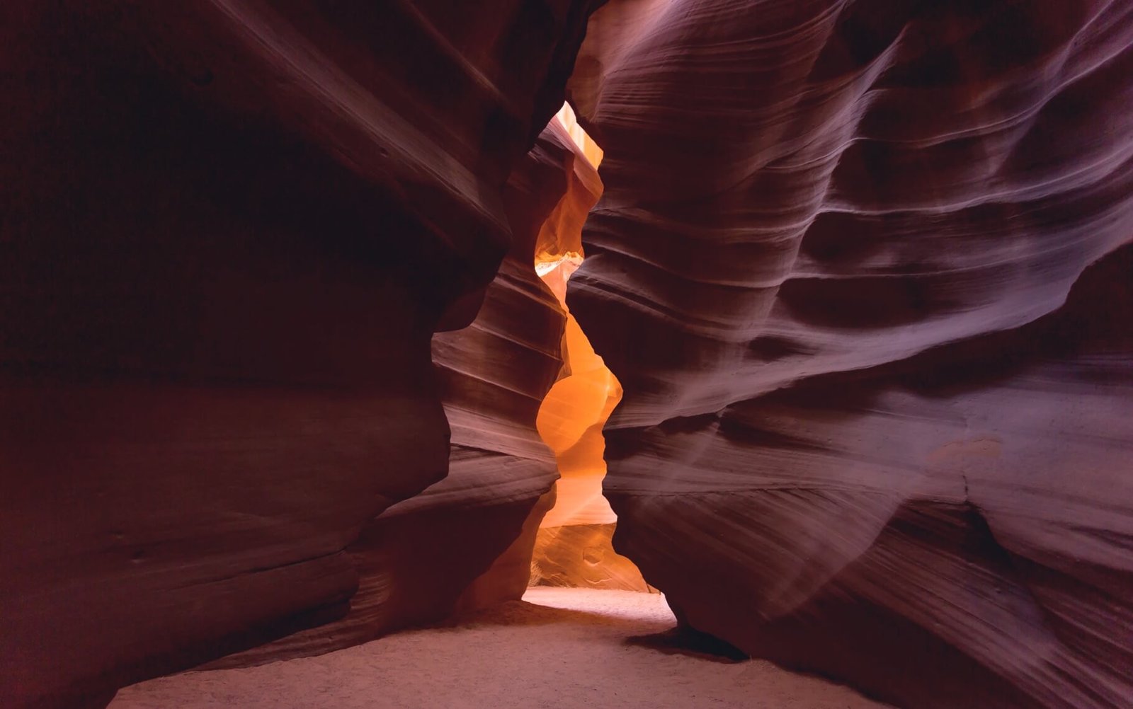Canyon walls with smooth, layered rock formations and a glowing orange light illuminating a narrow passageway, symbolizing creative freedom and design possibilities.