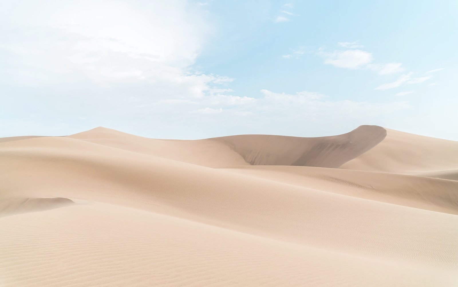 Vast sandy dunes under a clear blue sky, showcasing the beauty of natural landscapes, representing the creative freedom and limitless possibilities in web design and digital solutions.